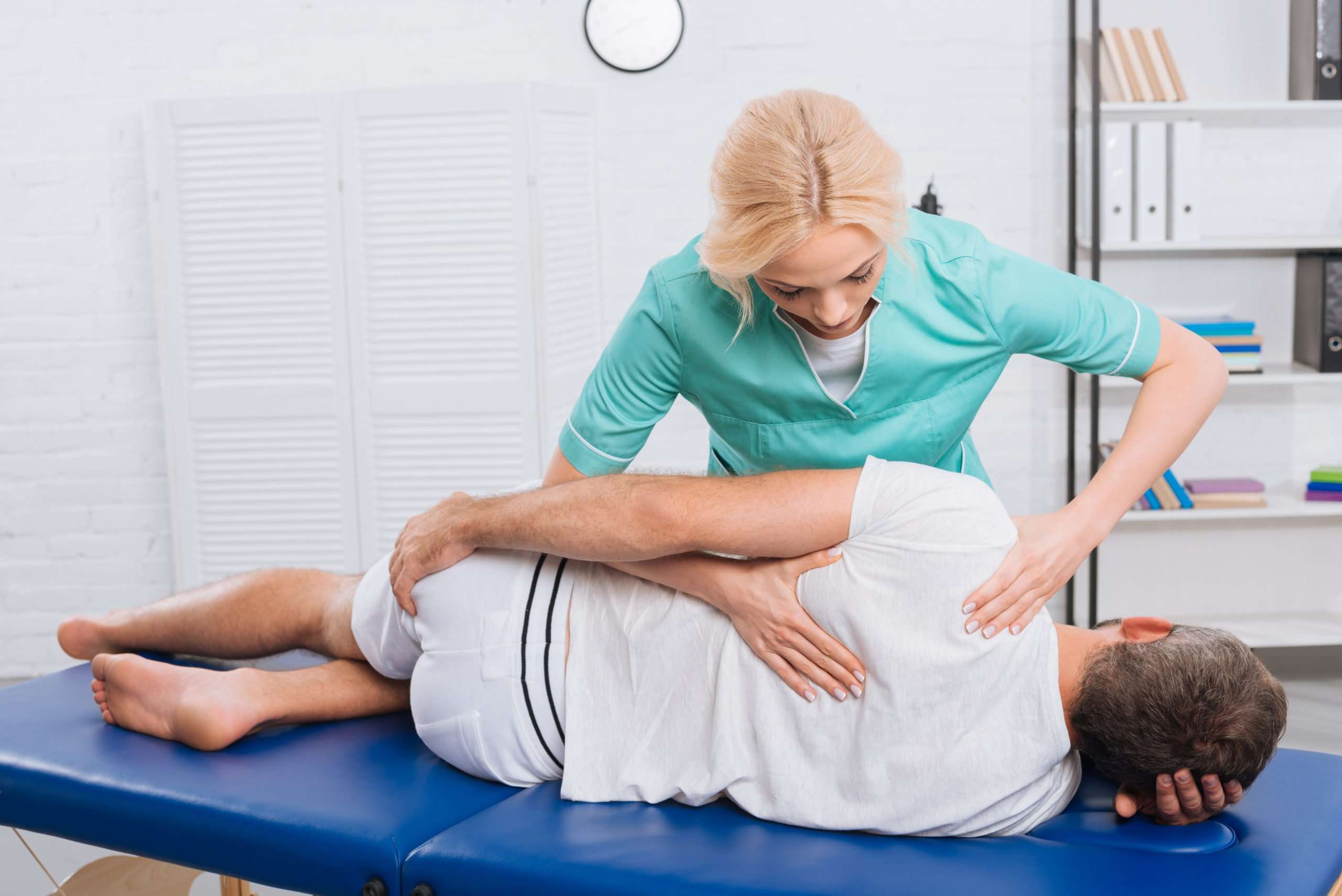 chiropractor massaging back on patient on massage table in hospital